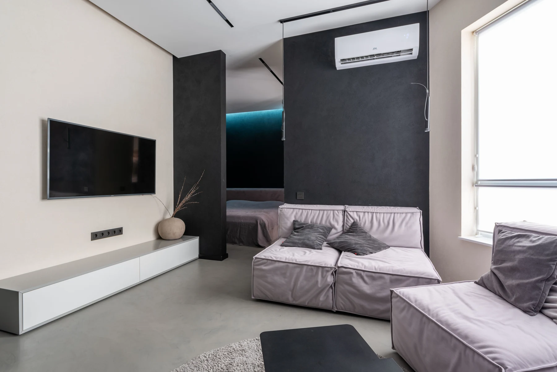 Điều hòa treo tường trong phòng khách hiện đại với sofa và cửa sổ lớn